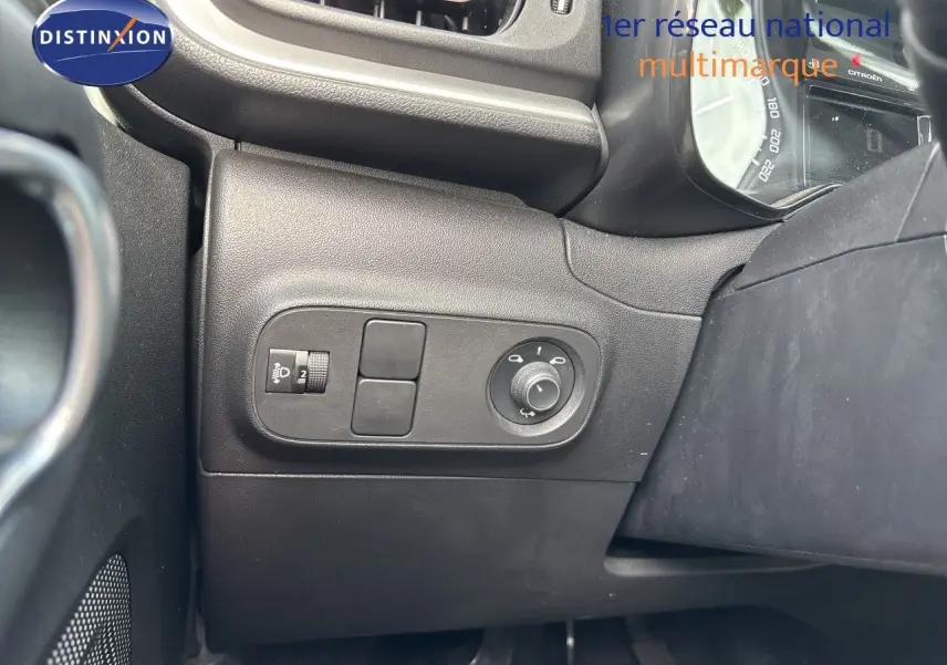 Détail du tableau de bord côté gauche de la Citroën C3 blanche, montrant les commandes de réglage des phares et des rétroviseurs.