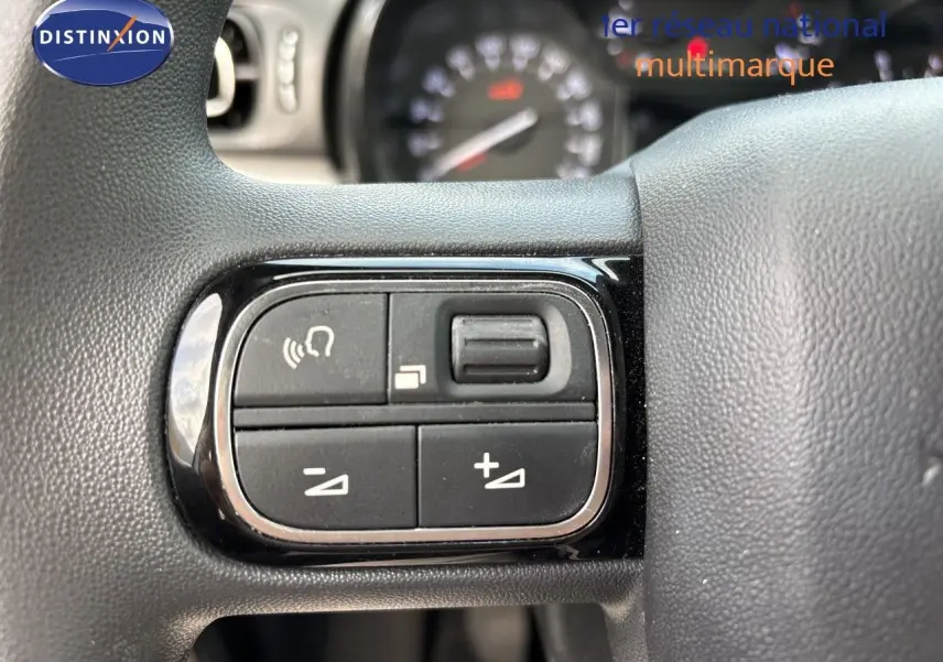 Gros plan sur les commandes de volume et téléphone intégrées au volant d'une Citroën C3 blanche banquise, 2022.