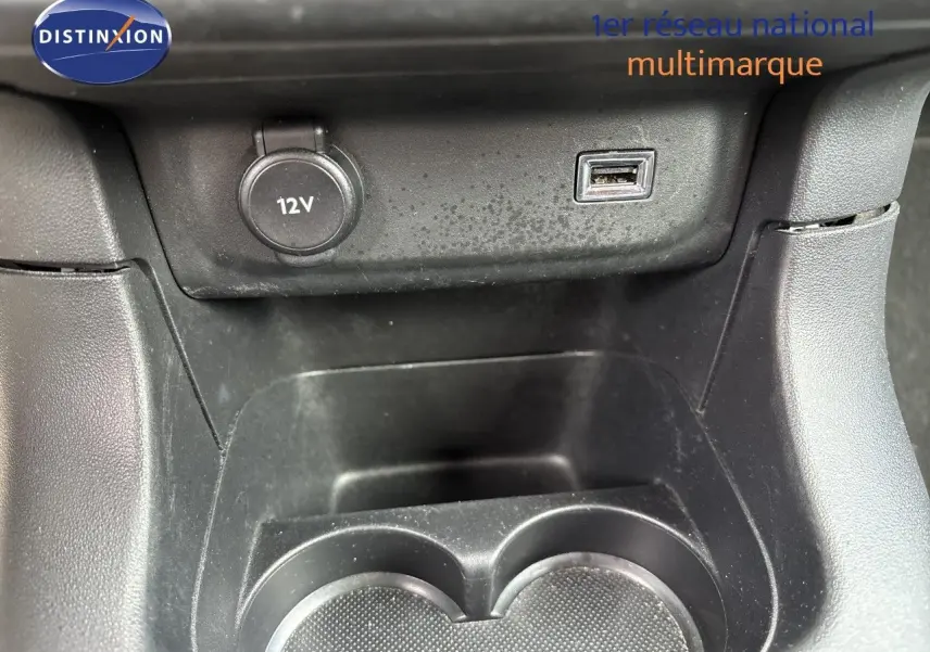 Gros plan sur la console centrale d’une Citroën C3 blanche, montrant prise 12V et port USB au-dessus des porte-gobelets.