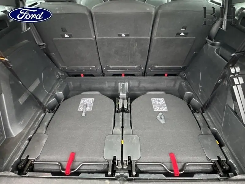 Vue arrière du coffre d'un Ford avec sièges arrière rabattus et garniture intérieure noire.