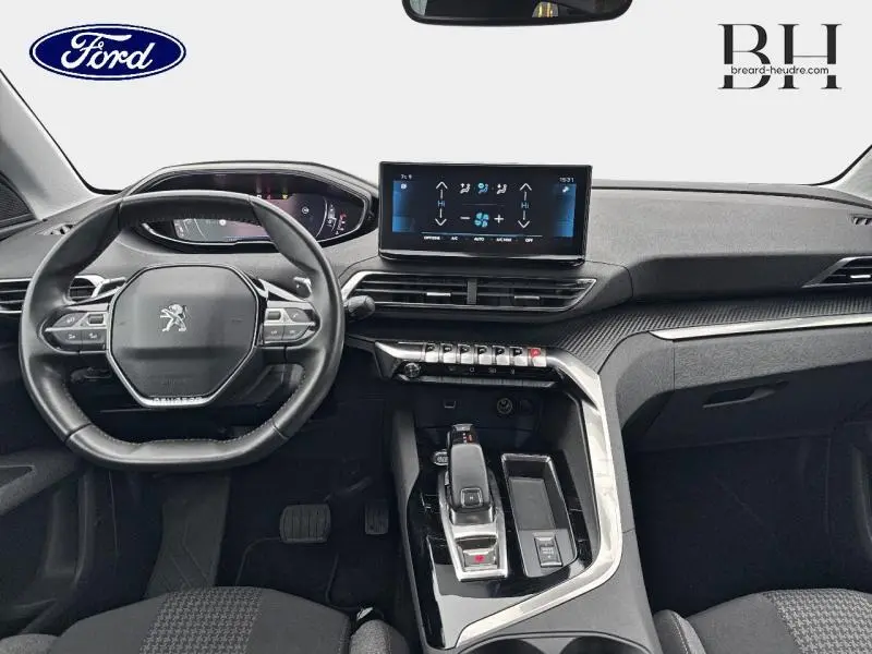 Intérieur avant du Peugeot 5008 gris Platinium, vue centrée sur le volant compact et l'écran tactile du tableau de bord.