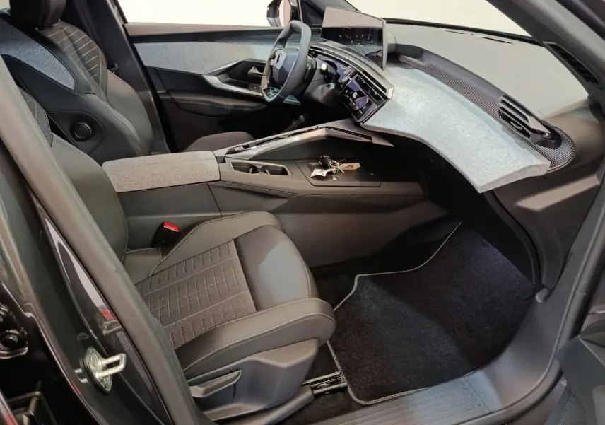 Vue intérieure côté conducteur du Peugeot 3008 1.2 Hybrid 145 GT 2025, avec tableau de bord moderne et sièges noirs.