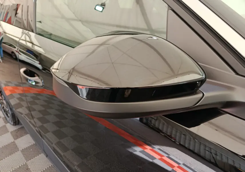 Rétroviseur côté gauche noir brillant du Peugeot 3008 2025, reflet du capot et de l'environnement intérieur.