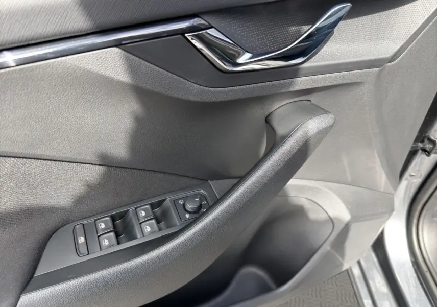 Vue rapprochée de la porte côté conducteur d’une Skoda Scala gris foncé, avec commandes électriques et poignée noire.