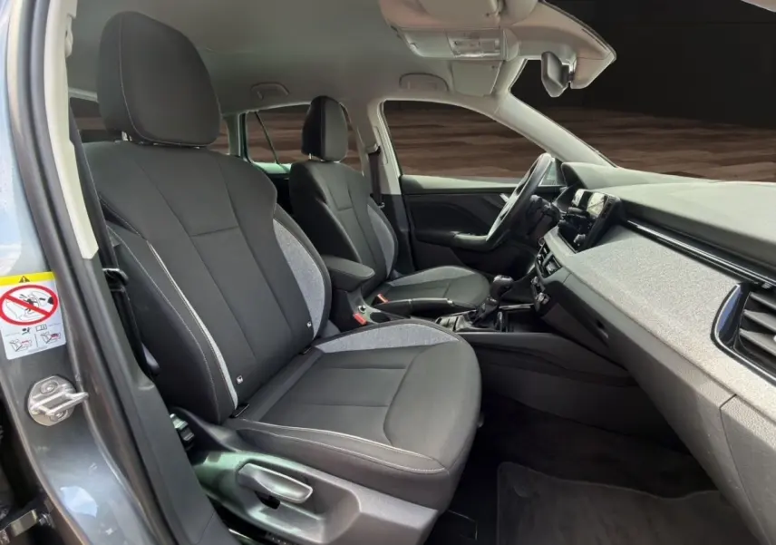 Vue intérieure côté conducteur de la Skoda Scala 2025 gris foncé, montrant sièges tissu bicolore et tableau de bord moderne.