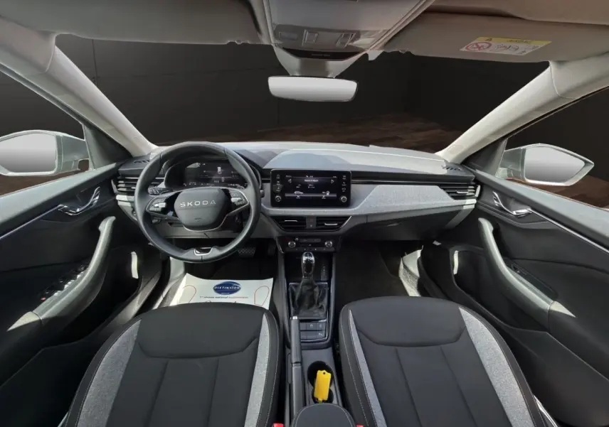 Vue intérieure avant de la Skoda Scala 2025, tableau de bord moderne gris et noir avec écran tactile central.