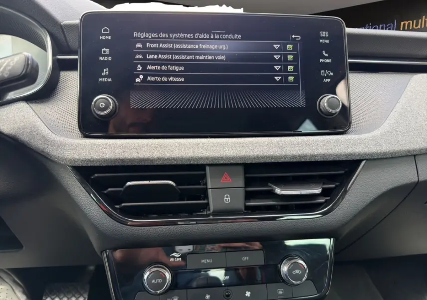 Vue rapprochée de l’écran tactile central et de la console de commande de la Skoda Scala 2025, affichant les réglages d’aide à la conduite.