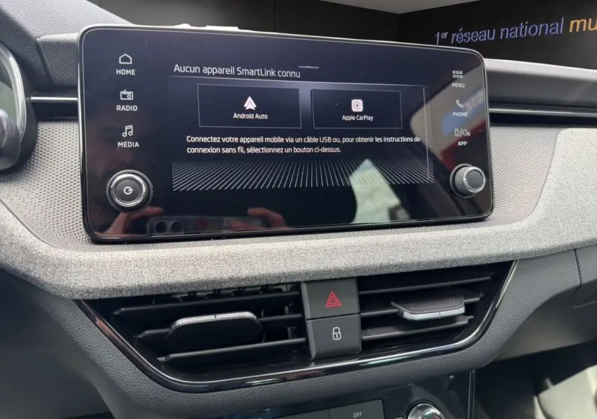 Vue rapprochée de l’écran tactile central et des commandes de ventilation du tableau de bord gris clair d’une Skoda Scala 2025.