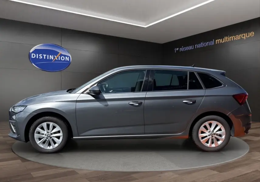 Profil côté gauche d'une Skoda Scala gris foncé exposée en intérieur avec jantes alliage et vitres teintées.