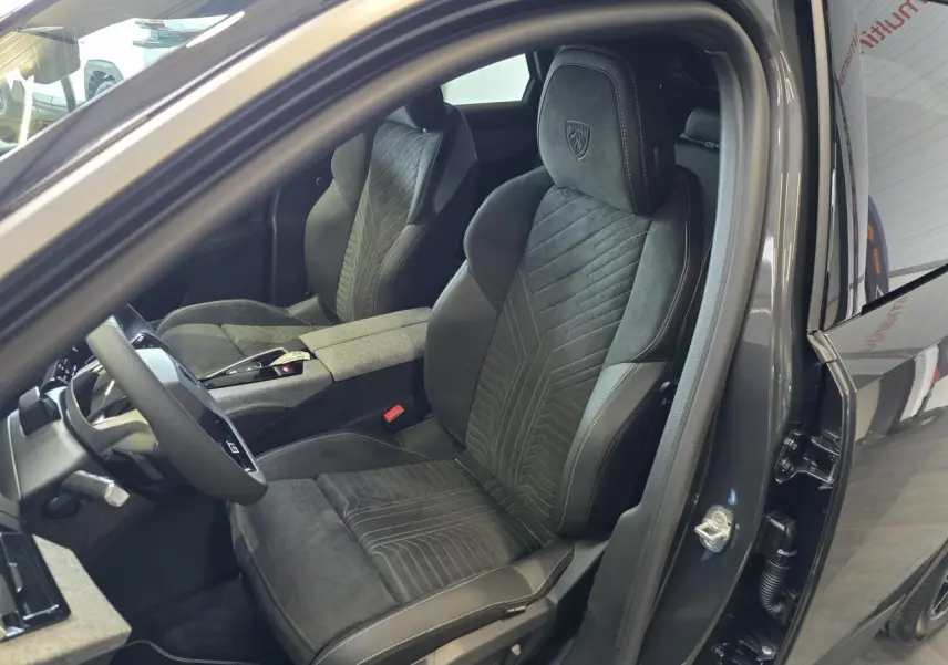 Vue intérieure côté conducteur du Peugeot 3008 2026 gris titanium, mettant en valeur les sièges sport en cuir et alcantara avec logo GT brodé.
