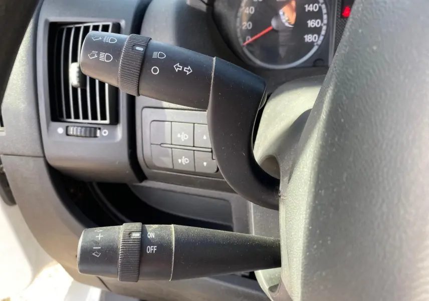 Gros plan sur les commandes de clignotants et essuie-glace du tableau de bord d'un Citroën Jumper blanc de 2013.