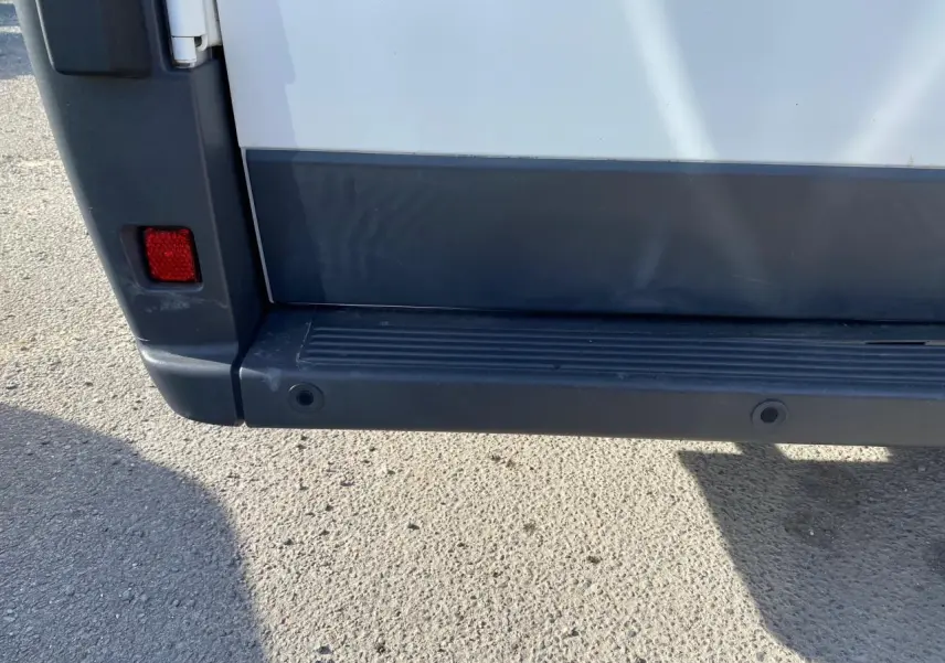 Gros plan sur le pare-chocs arrière noir et blanc du Citroën Jumper 2013 avec attelage visible en bas.