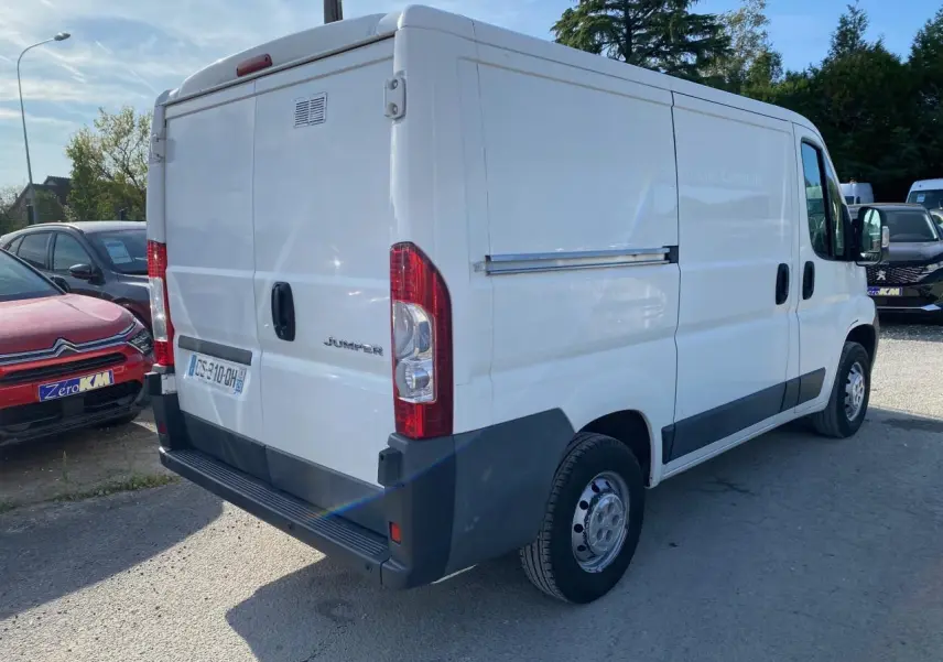 Vue 3/4 arrière droite d'un utilitaire blanc Citroën Jumper 2013 avec attelage et hayon arrière fermé.