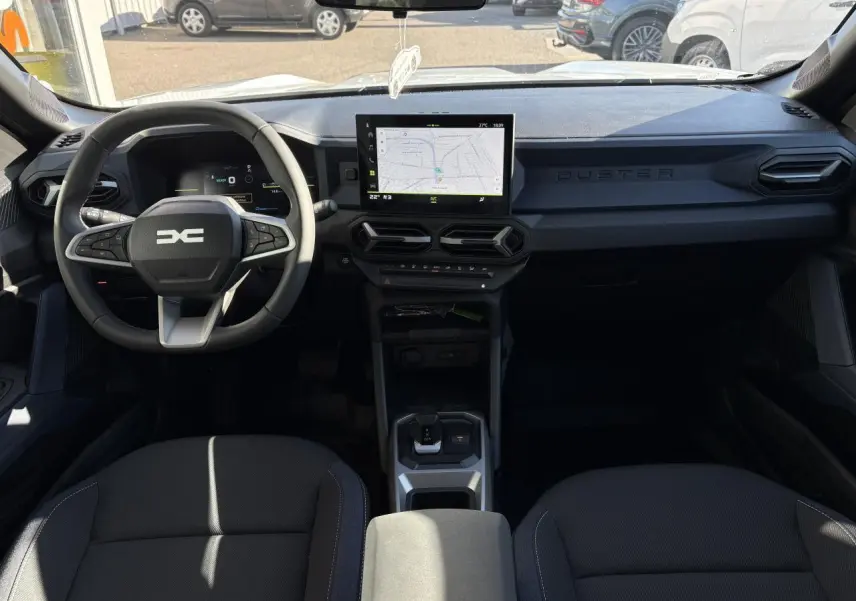 Vue intérieure avant du Dacia Duster 2024 avec tableau de bord digital et écran tactile central affichant une carte.