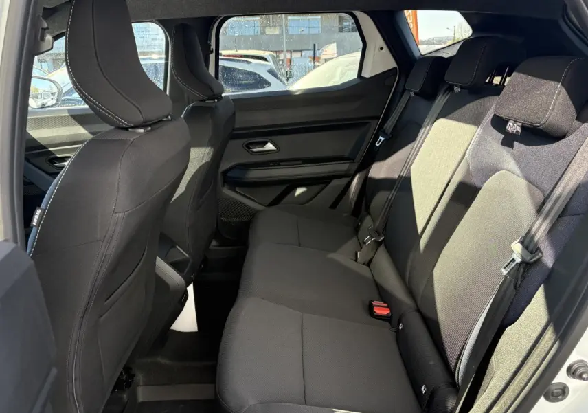 Vue intérieure côté droit sur la banquette arrière noire du Dacia Duster 1.6 Hybrid 2024 blanc métallisé.