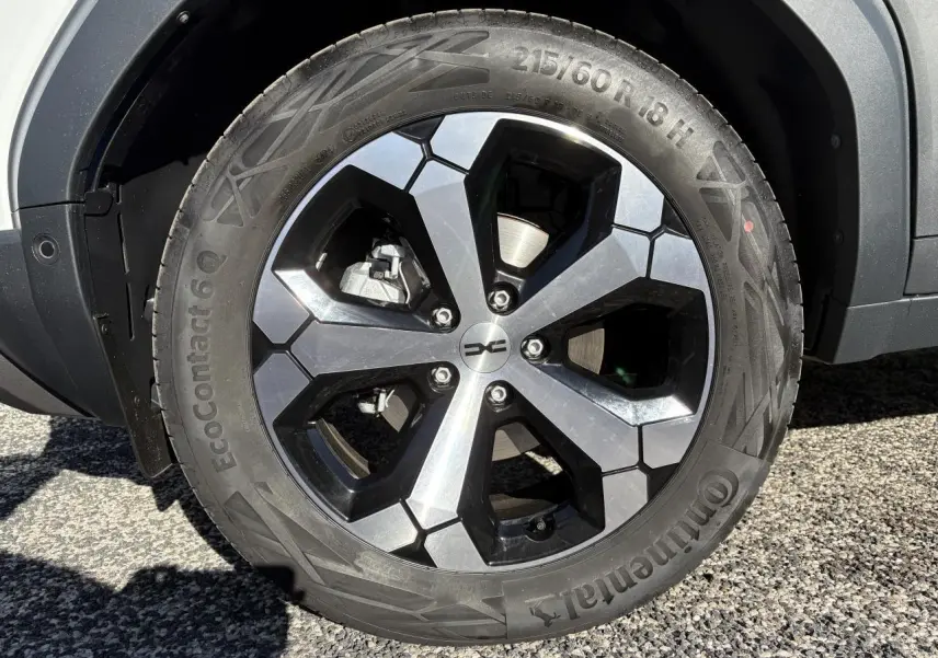 Gros plan sur la roue arrière droite du Dacia Duster blanc métallisé 2024 avec passage de roue noir mat.