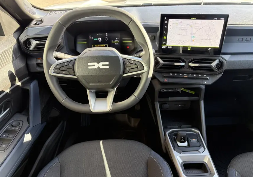 Vue intérieure du tableau de bord et volant du Dacia Duster 1.6 Hybrid 2024 avec écran tactile et sellerie Denim.