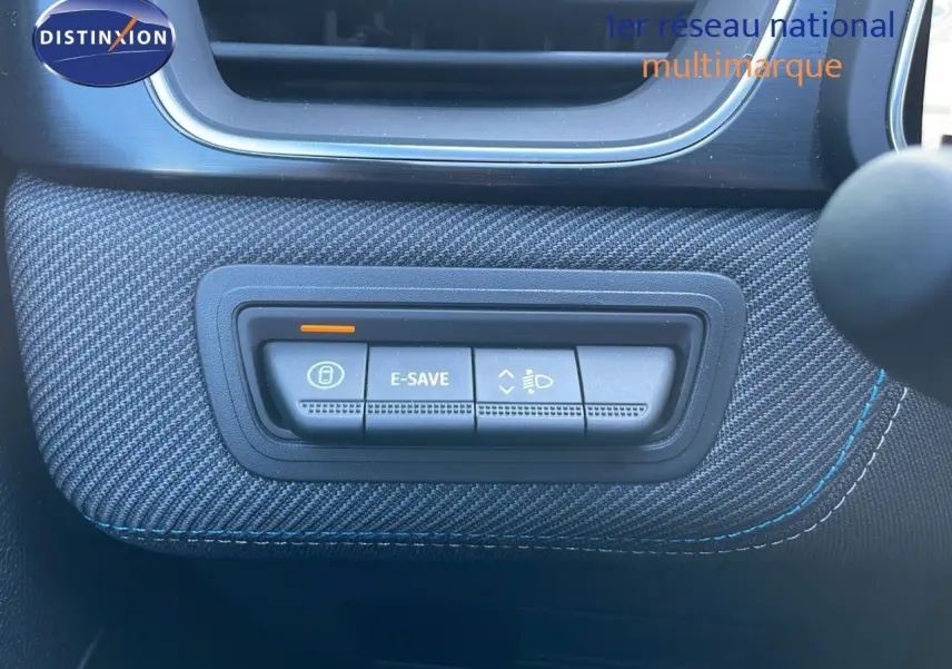 Gros plan sur les commandes E-SAVE et réglage des phares sur tableau de bord tissu bleu du Renault Captur hybride 2025.
