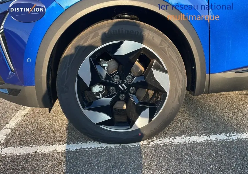 Gros plan sur la roue avant gauche d'un Renault Captur bleu Iron Metal avec jante noire et grise design moderne.