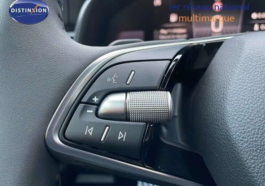 Gros plan sur les commandes audio au volant du Skoda Kamiq gris graphite, avec molette texturée et boutons multifonctions.