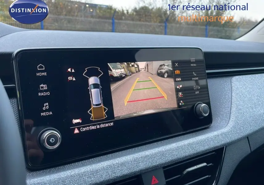 Écran central du Skoda Kamiq gris graphite montrant la caméra de recul avec guidage de trajectoire en ville.