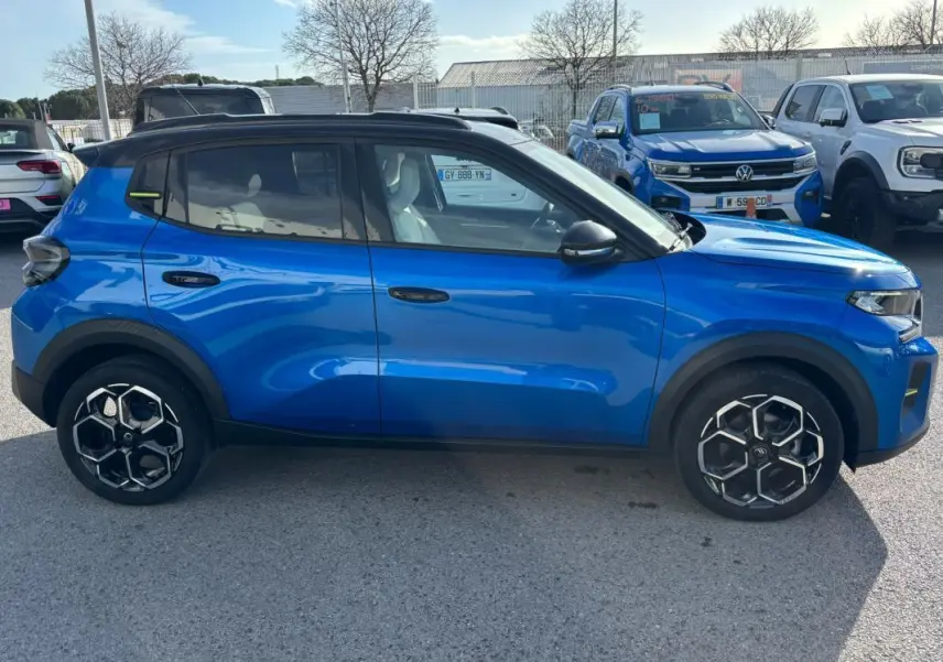 Vue latérale droite d'une Citroën C3 bleu 2025 avec jantes alliage noires et barres de toit visibles.