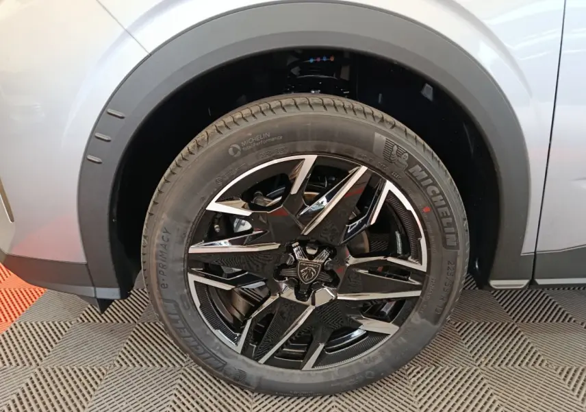 Gros plan sur la roue avant droite du Peugeot 3008 gris clair, jante alliage noire et argentée avec logo lion.