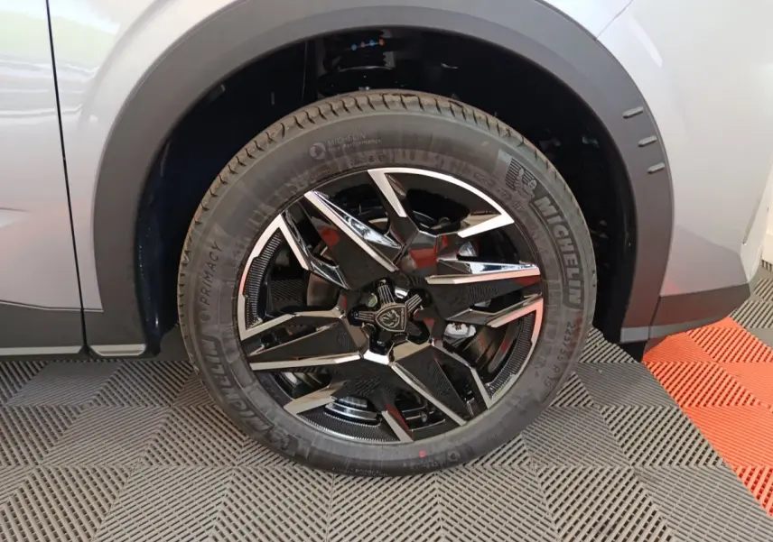 Gros plan sur la roue avant gauche du Peugeot 3008 gris clair, avec jante alliage noire et détails chromés.