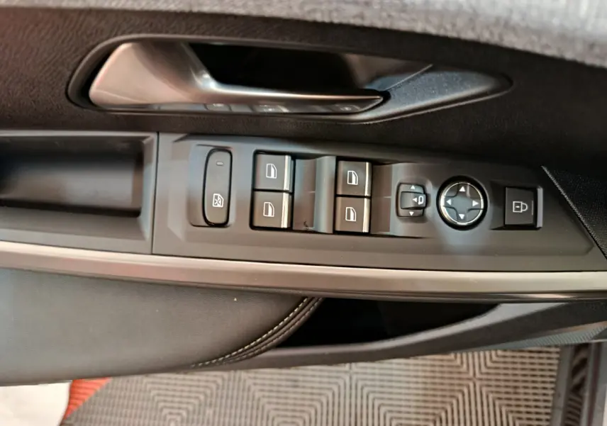 Gros plan sur la commande des vitres et rétroviseurs côté conducteur du Peugeot 3008 gris clair, intérieur cuir noir.