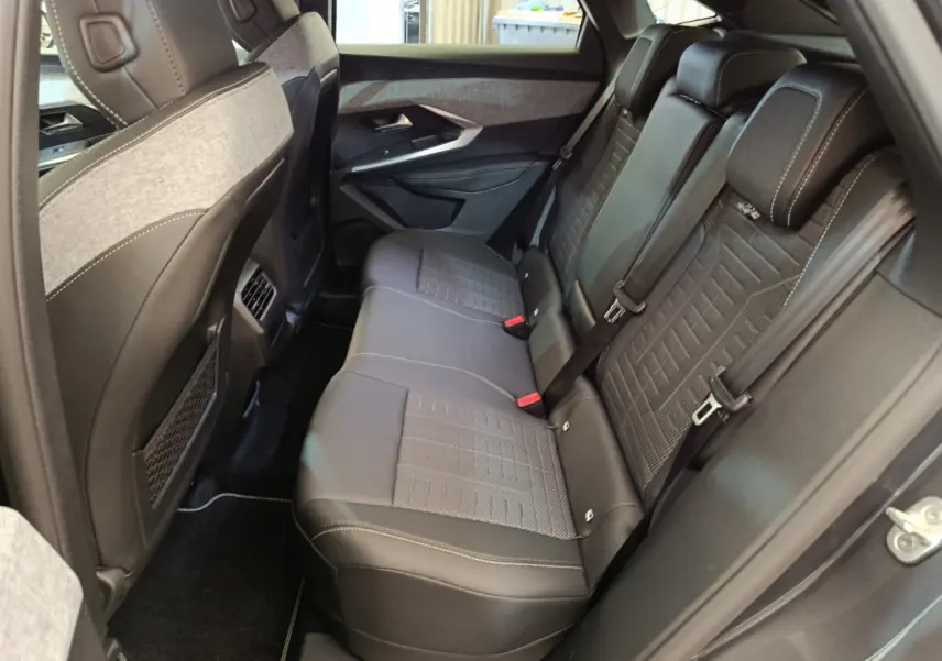 Vue côté droit de l’habitacle arrière du Peugeot 3008 gris clair, sièges en cuir noir avec surpiqûres blanches.