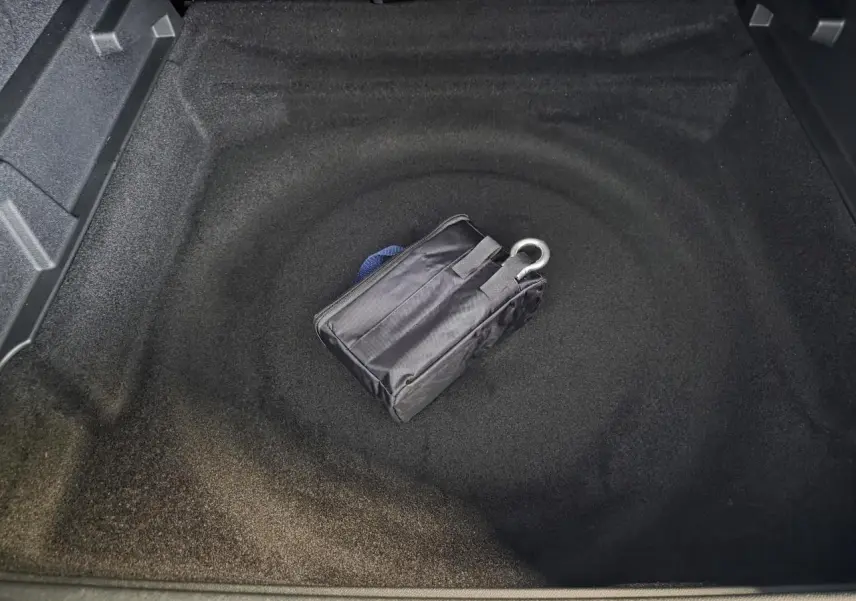 Coffre ouvert du Peugeot 3008 bleu, montrant le rangement sous plancher avec kit de dépannage pneumatique.