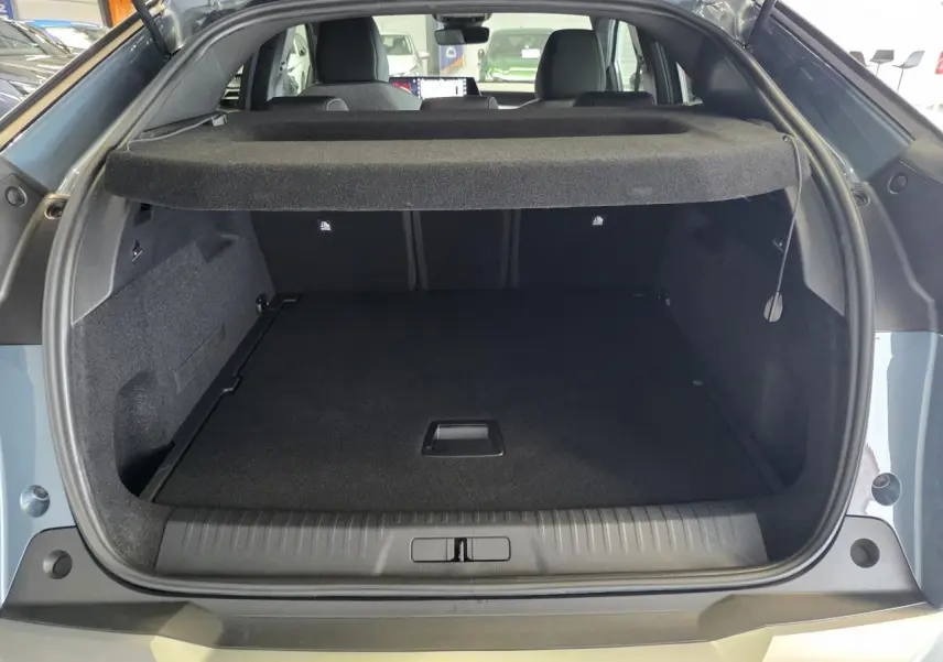 Coffre ouvert vu de l'arrière d'un Peugeot 3008 bleu hybride 2026, avec cache-bagages et intérieur noir.