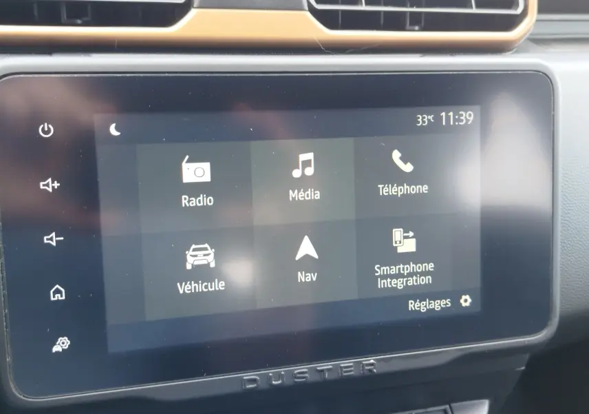 Écran tactile central du Dacia Duster 2024 en gros plan, affichant les options radio, média, téléphone et navigation.