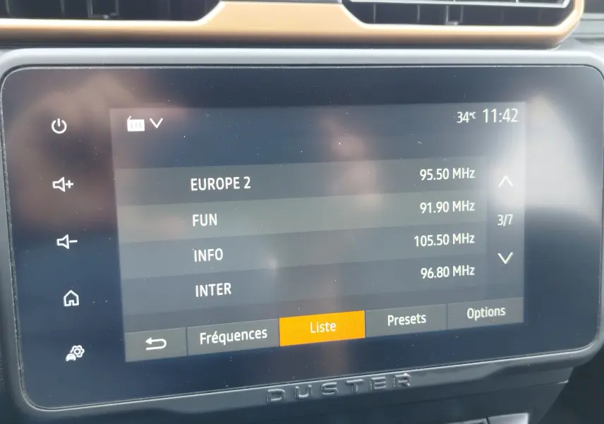 Écran tactile central du Dacia Duster 2024 affichant la liste des stations radio FM avec interface moderne.