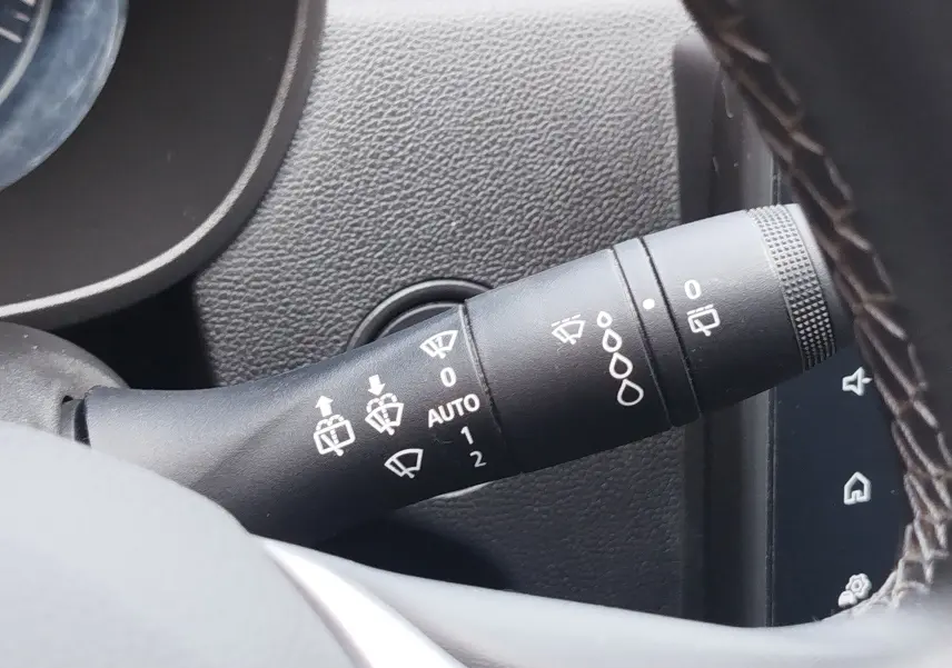 Gros plan sur la commande des essuie-glaces du Dacia Duster 2024, intérieur noir avec détails blancs sur levier.