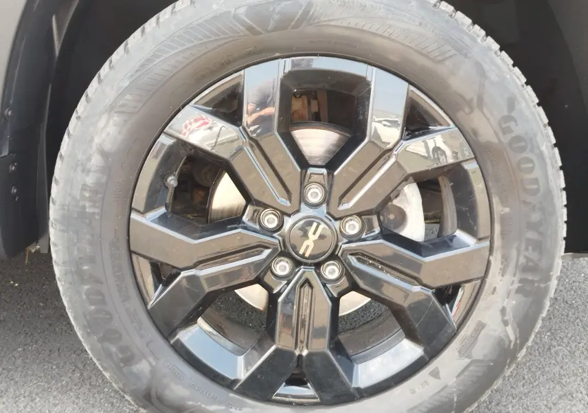 Gros plan sur la jante noire brillante du Dacia Duster 2024, avec pneu Goodyear et logo Extreme au centre.