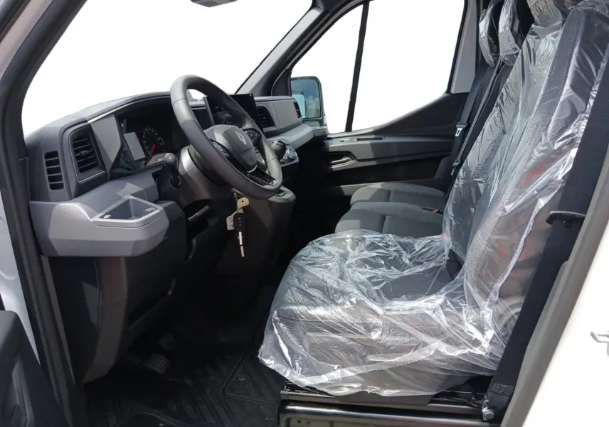Vue intérieure côté conducteur du Renault Master blanc 2026, sièges protégés par film plastique, volant et tableau de bord visibles.