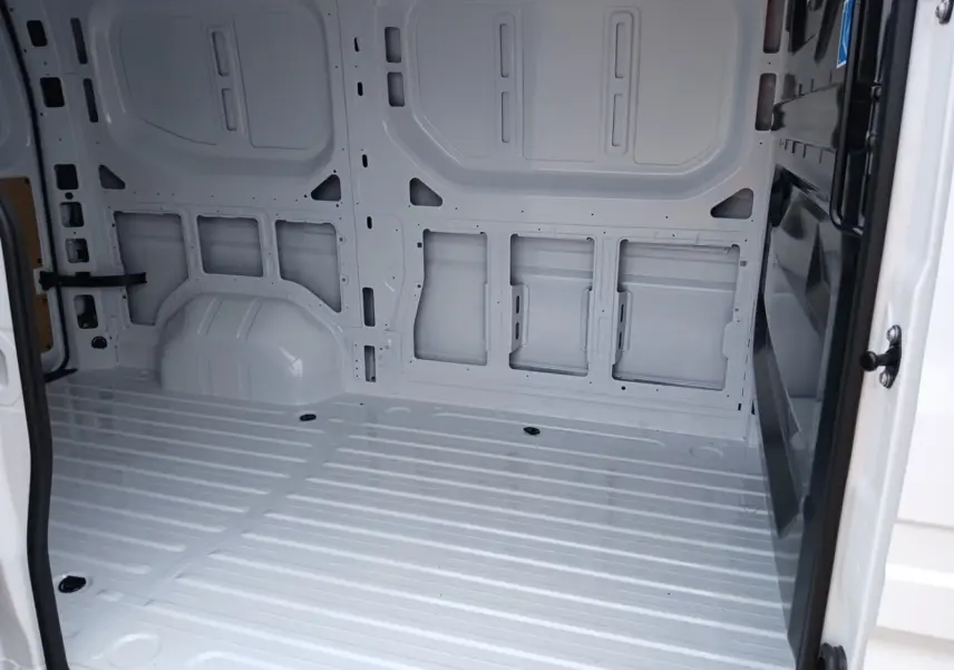 Intérieur vide du Renault Master blanc vu depuis l'ouverture latérale droite, montrant la structure métallique du fourgon.