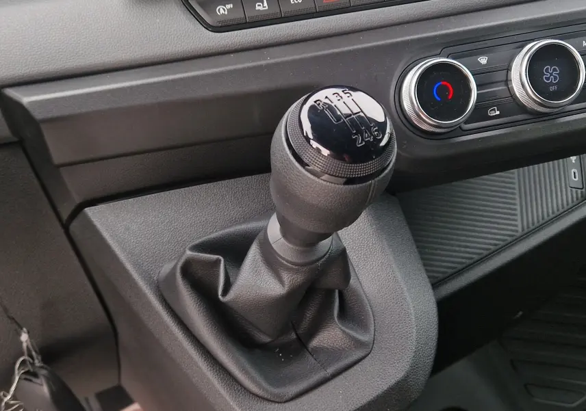 Gros plan intérieur sur le levier de vitesses manuel noir du Renault Master L2H2 2026 avec commandes de climatisation visibles.