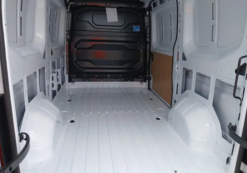Vue intérieure arrière du Renault Master blanc L2H2, montrant l'espace de chargement vide avec cloison noire et paroi latérale partiellement protégée.