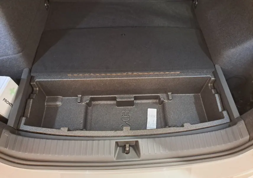 Coffre ouvert vu de dessus du Skoda Kodiaq gris perle, montrant le rangement sous plancher et une trousse de secours.