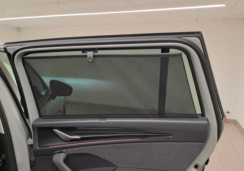 Vue intérieure de la porte arrière gauche d'un Skoda Kodiaq gris perle avec pare-soleil intégré et poignée argentée.