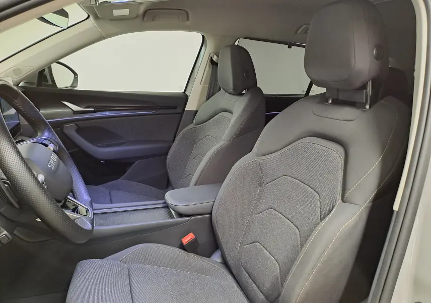Vue intérieure côté conducteur du Skoda Kodiaq gris perle 2025, sièges tissu gris avec coutures contrastées.