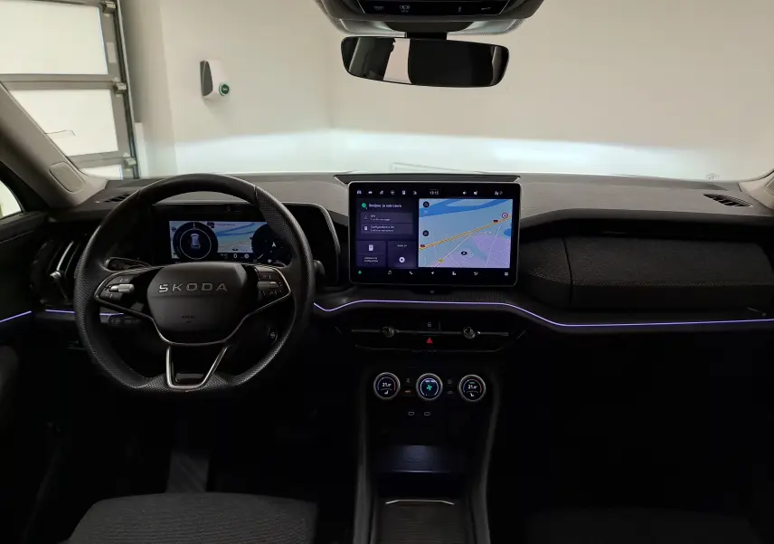 Intérieur du Skoda Kodiaq 2025, vue frontale du tableau de bord avec écran tactile central et éclairage d'ambiance violet.
