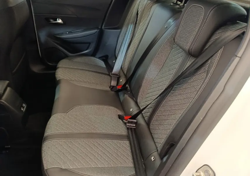 Vue côté droit sur la banquette arrière grise et noire du Peugeot 208 électrique blanc 2024, avec ceintures attachées.
