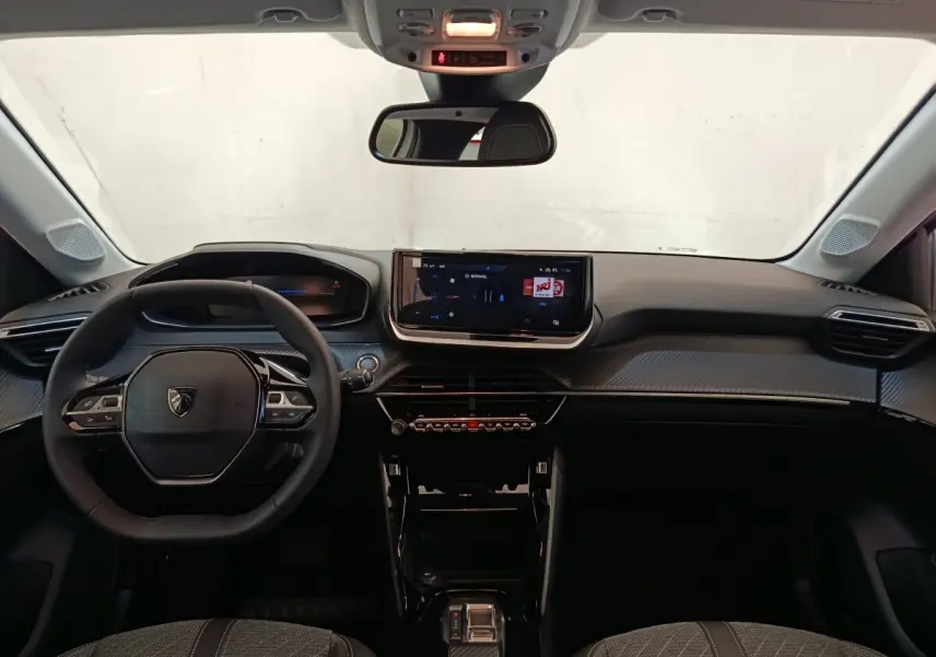 Vue frontale de l'intérieur du Peugeot 208 électrique blanc 2024, avec tableau de bord numérique et écran tactile central.