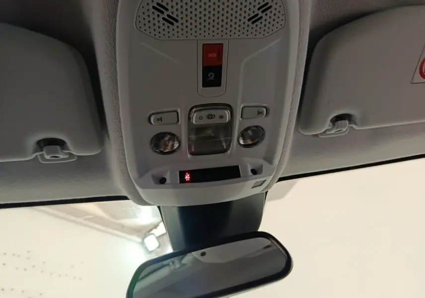 Plafonnier intérieur avec commandes d’éclairage et bouton SOS, rétroviseur central dans un Peugeot 208 blanc 2024.