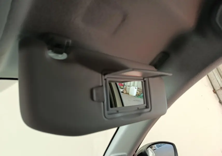 Miroir de courtoisie ouvert sur pare-soleil côté conducteur dans l’habitacle d’une Peugeot 208 électrique blanche.