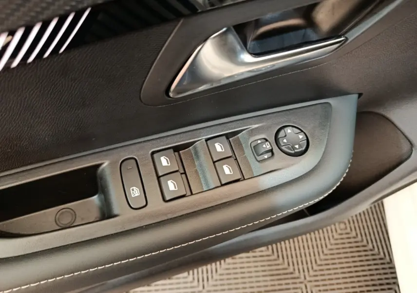 Gros plan sur la commande des vitres électriques et réglage des rétroviseurs côté conducteur de la Peugeot 208 blanche 2024.