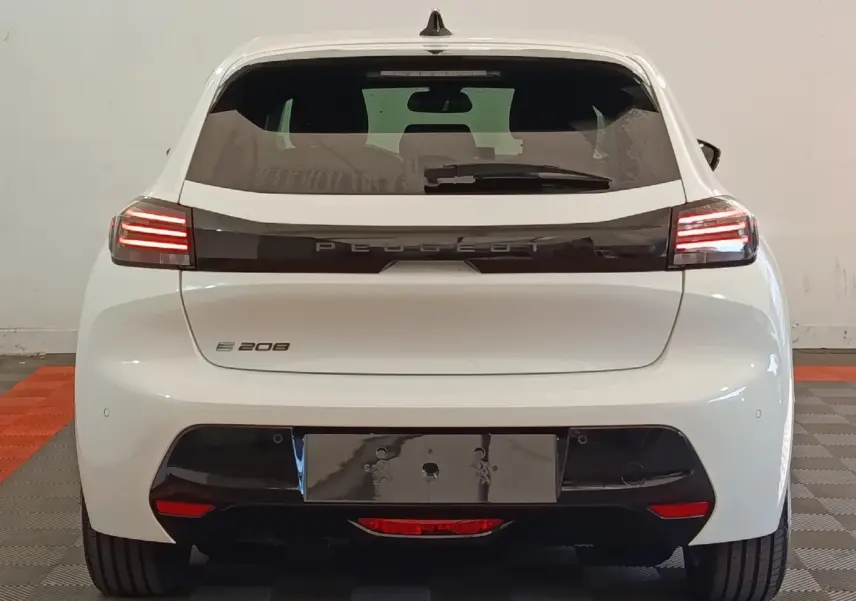 Vue arrière d'une Peugeot 208 électrique blanche 2024 avec feux LED et bande noire distinctive sur le hayon.